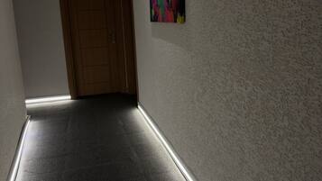 Un pasillo con una puerta de madera, un pared texturizado y un cuadro abstracto colorido.