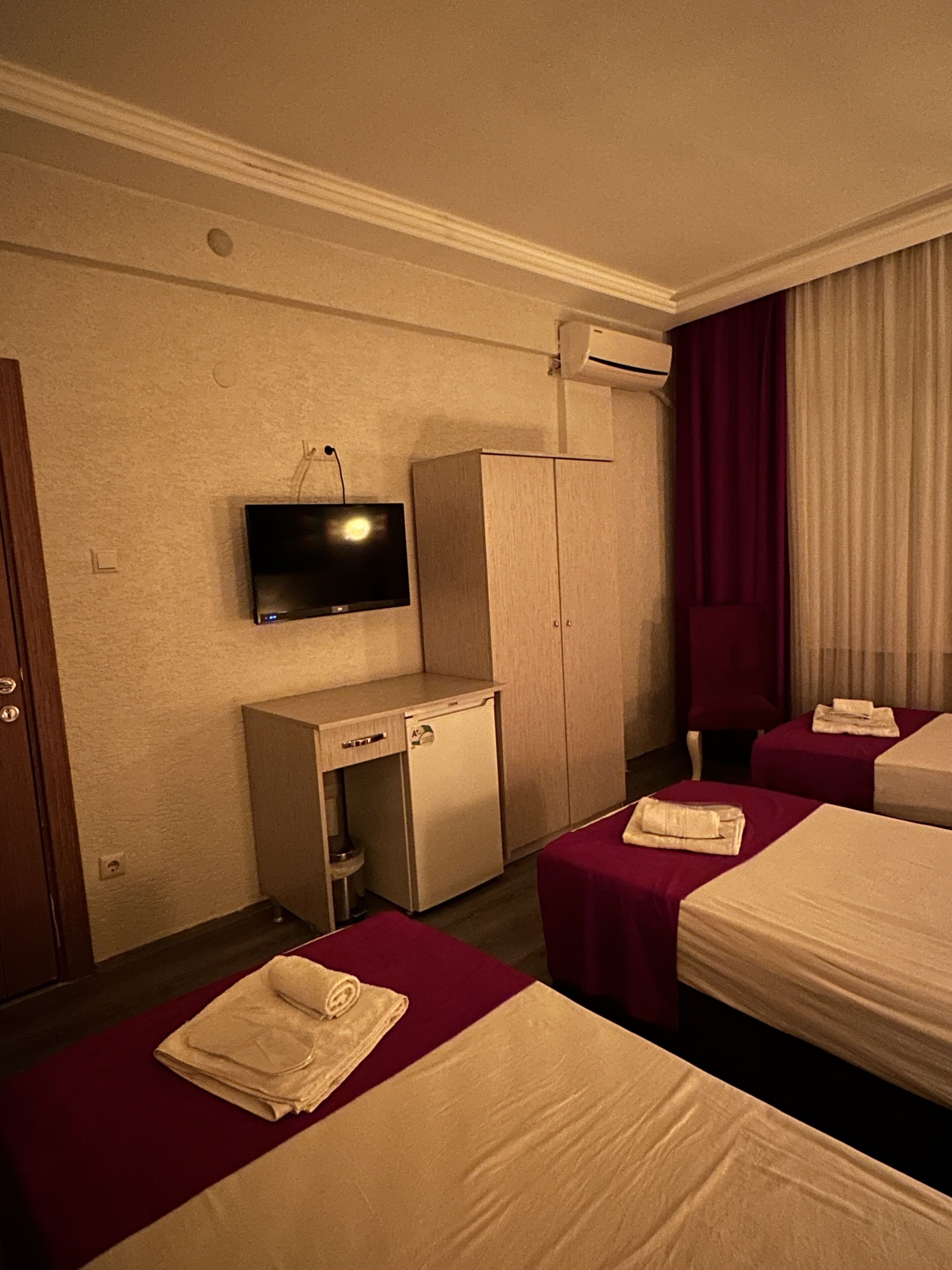 A hotel room with two beds, a desk, a television, and a wardrobe.