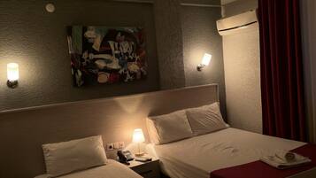 Habitación de hotel con dos camas, un cuadro en la pared, una lámpara y un teléfono en la mesita de noche.