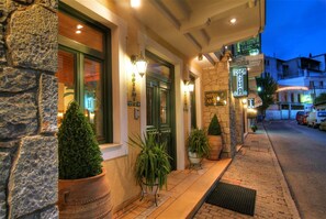 Fachada de piedra con puerta verde, plantas en macetas y un letrero que indica un hotel.