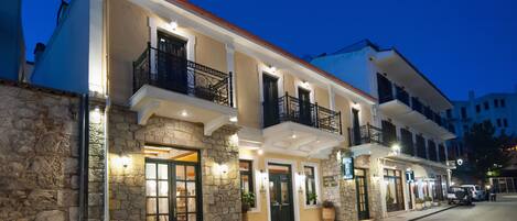 A hotel with a stone facade, multiple balconies, and illuminated entrance doors.