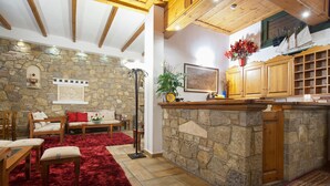 Ein gemütliches Interieur mit Steinwand, Holzmöbeln, einem roten Teppich und einer Küchenzeile mit Holzausbau.
