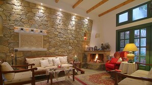Ein gemütliches Wohnzimmer mit Steinwand, Kamin und bequemen Sitzmöglichkeiten.