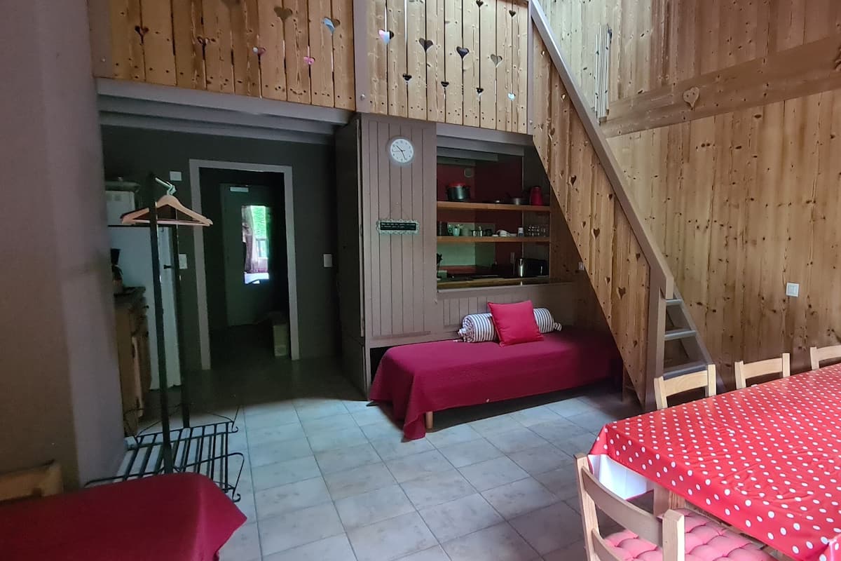 A wooden interior with a bed, a table, and a staircase.