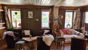A cozy room with wooden walls, a sofa, chairs, and a small table with a plant. - Hôtel Restaurant L'Adray (Aime-la-Plagne)