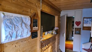 A wooden interior with a reception desk, a map, a heart-shaped decoration, and a sign indicating a bar and restaurant. - Hôtel Restaurant L'Adray (Aime-la-Plagne)