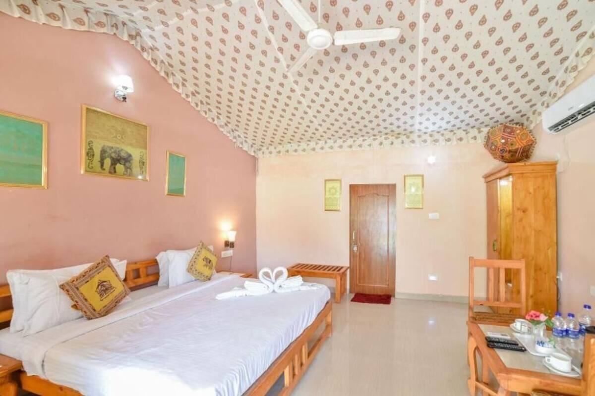 A hotel room with a bed, a desk, a chair, and a ceiling fan.
