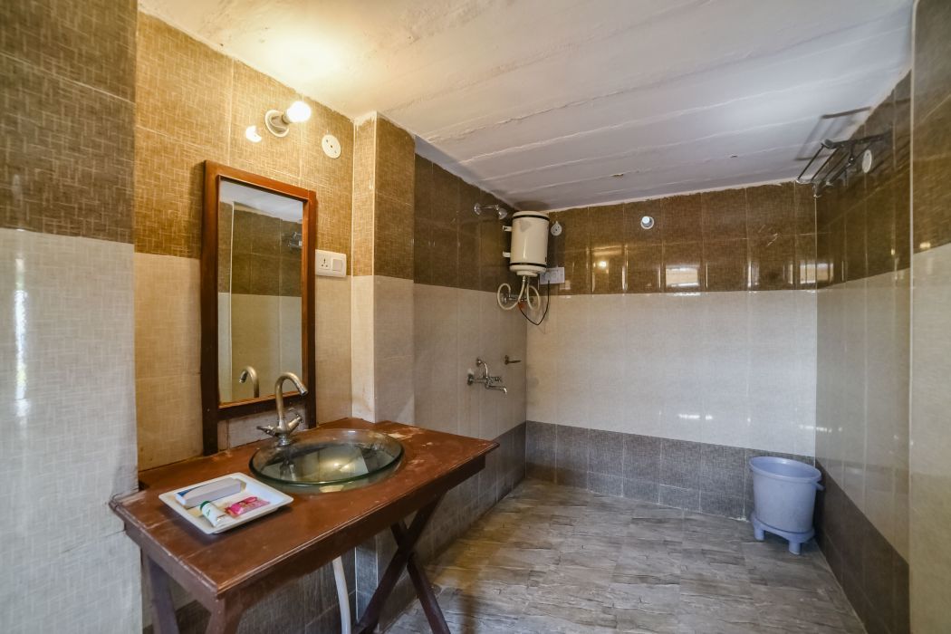 A bathroom with a wooden vanity, a glass sink, a mirror, a towel rack, and a shower area.