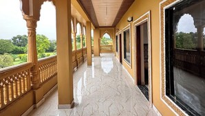 A corridor with marble flooring, wooden ceiling, and large windows offering a view of greenery. - Pushkar Rajwara Resort (Pushkar)
