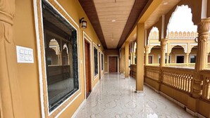 A corridor with marble flooring, ornate columns, and a view of a building with arches. - Pushkar Rajwara Resort (Pushkar)