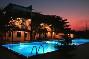 A swimming pool with a modern building in the background. - Hotel Freedom Village (Dambulla)