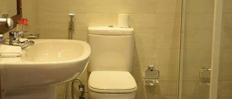 Baño con lavamanos, inodoro y cabina de ducha de vidrio.