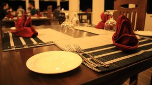 A dining table set with plates, cutlery, and napkins. - Hotel Freedom Village (Dambulla)
