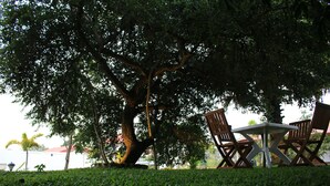 A table and chairs under a large tree in a park setting. - Hotel Freedom Village (Dambulla)