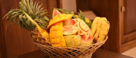 Una cesta de mimbre con fruta sobre una mesa de madera.