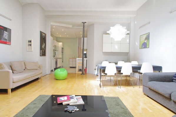 A modern living room with a sofa, a coffee table, and a dining area with chairs and a table. - The London Agent The Strand (London)