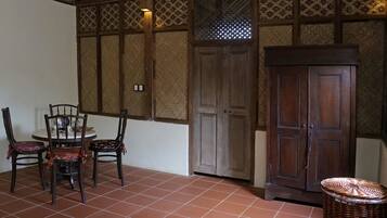 Une pièce avec un sol carrelé, une table ronde entourée de chaises, un meuble en bois et un panier en osier.