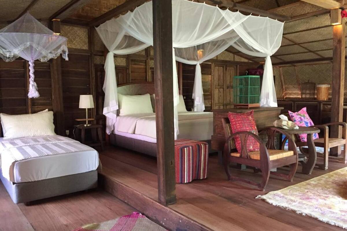 A traditional wooden room with a bed, a chair, and a table.