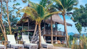 A wooden deck with lounge chairs, a thatched-roof structure, and a pond with lily pads. - Kunang-Kunang Heritage Villas (Langkawi)