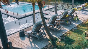 A wooden deck with lounge chairs and a pool. - Kunang-Kunang Heritage Villas (Langkawi)