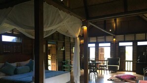 A room with a bed, a dining area with chairs, and a view of the outside. - Kunang-Kunang Heritage Villas (Langkawi)