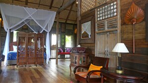 A traditional room with a bed, a wooden chair, a table, and a decorative fan. - Kunang-Kunang Heritage Villas (Langkawi)