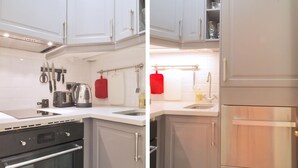 A modern kitchen with white cabinets, stainless steel appliances, and a red towel hanging on a rack. - The London Agent Hyde Park King Bed (London)
