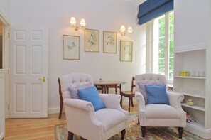 Una habitación con dos sillones tapizados, una mesa de comedor de madera y una estantería.