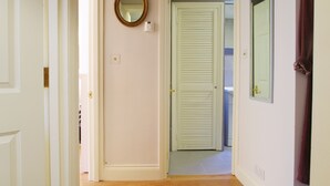 A hallway with a closed door, a mirror on the wall, and a towel hanging on the right. - The London Agent Hyde Park King Bed (London)