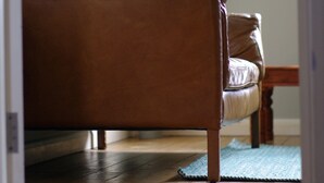A room with a wooden floor, a brown sofa, a green plant, and a framed picture on the wall. - The London Agent Waterloo Comfortable Home (London)