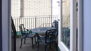 A view through a glass door into a balcony with a metal table and chairs, a brick wall, and a metal railing. - The London Agent Waterloo Comfortable Home (London)
