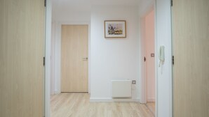 A hallway with wooden flooring, a radiator, and a framed picture on the wall.