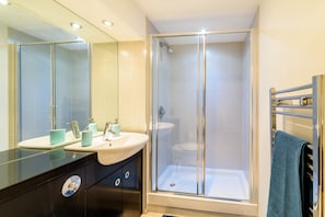 A modern bathroom with a glass-enclosed shower, a vanity with a sink, and a towel rack.