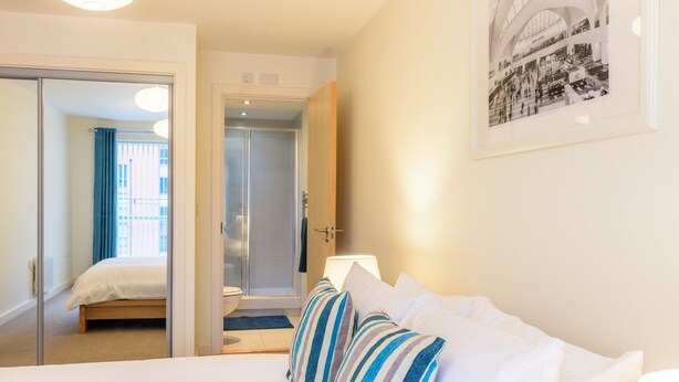 A hotel room with a bed, a bathroom, and a hallway.