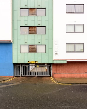 A building with a green facade, multiple windows, and a gated entrance.
