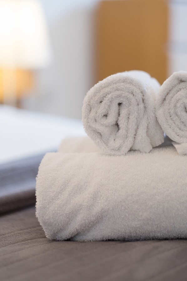 A neatly folded white towel on a wooden surface, likely in a hotel room.