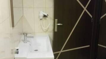Un baño con un lavamanos blanco, un espejo y una puerta oscura con un diseño en forma de X blanca.