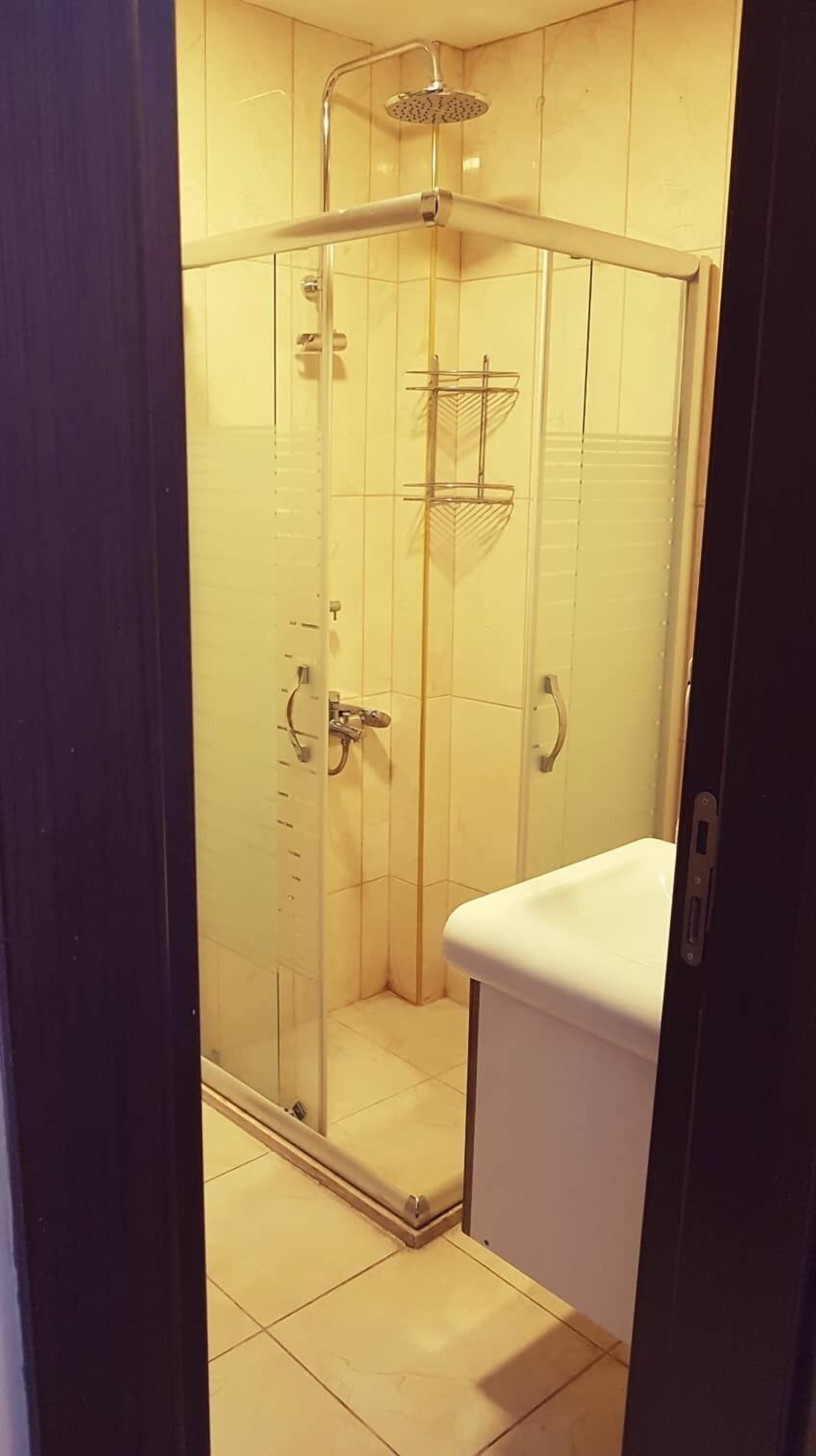 A glass-enclosed shower stall with a white sink and a showerhead.