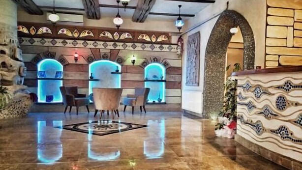 Una hall con pavimento in marmo, travi in legno a soffitto e una reception con dettagli in mosaico.