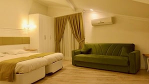 A bedroom with a bed, a green sofa, and a wardrobe. - Lotus Apart Pansiyon (Koycegiz)