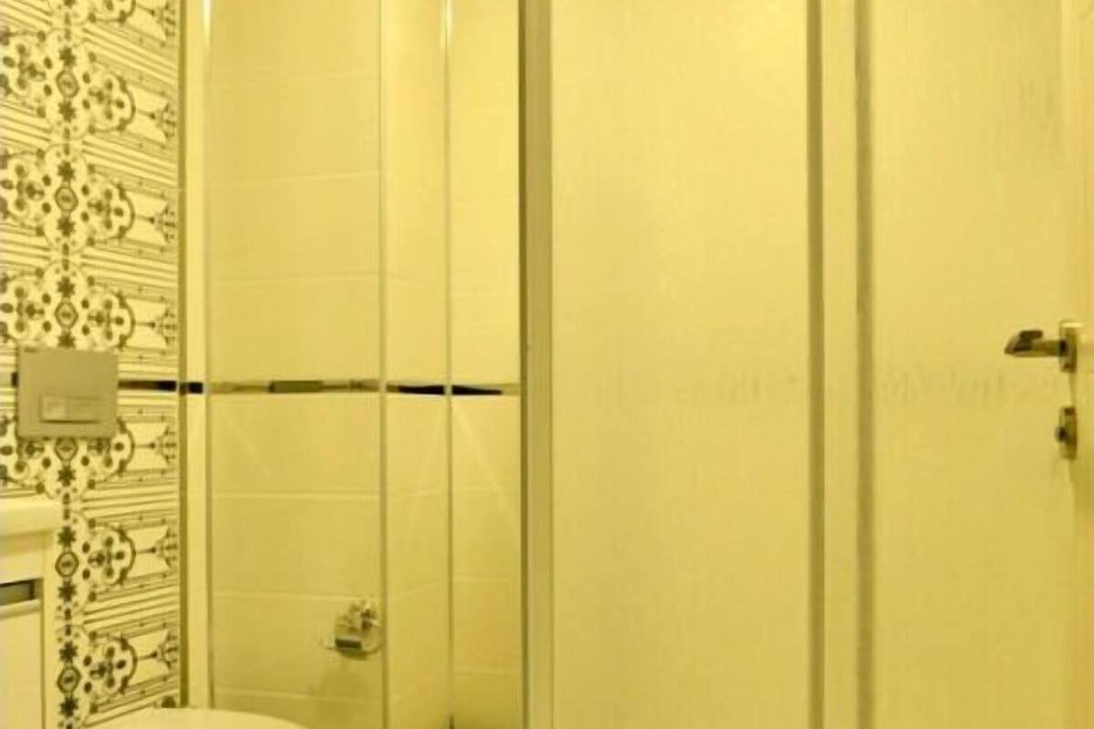A bathroom with a toilet, a shower with a glass door, and a trash can.