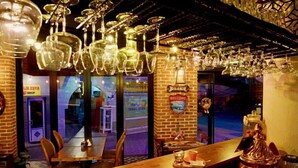 A bar area with hanging glassware, a wooden counter, and a brick wall with a 'Welcome' sign. - Lotus Apart Pansiyon (Koycegiz)