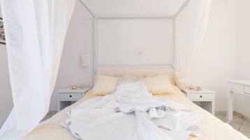 Un dormitorio con cama con dosel, dos mesitas de noche y un tocador.