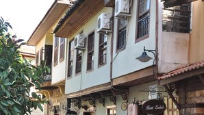 A narrow street with buildings featuring traditional architecture, including balconies and wooden shutters. - Kont Pansiyon (Antalya)