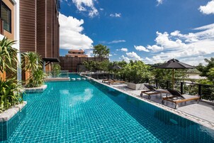 Una piscina al aire libre, sillones reclinables de piscina