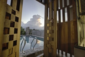 Une cloison en bois donnant sur la piscine, des marches en pierre et une main courante en métal.