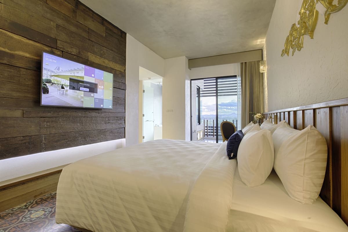 Habitació d'hotel amb un llit gran, televisió de pantalla plana penjada a la paret i vista a l'exterior a través d'una finestra ampla.