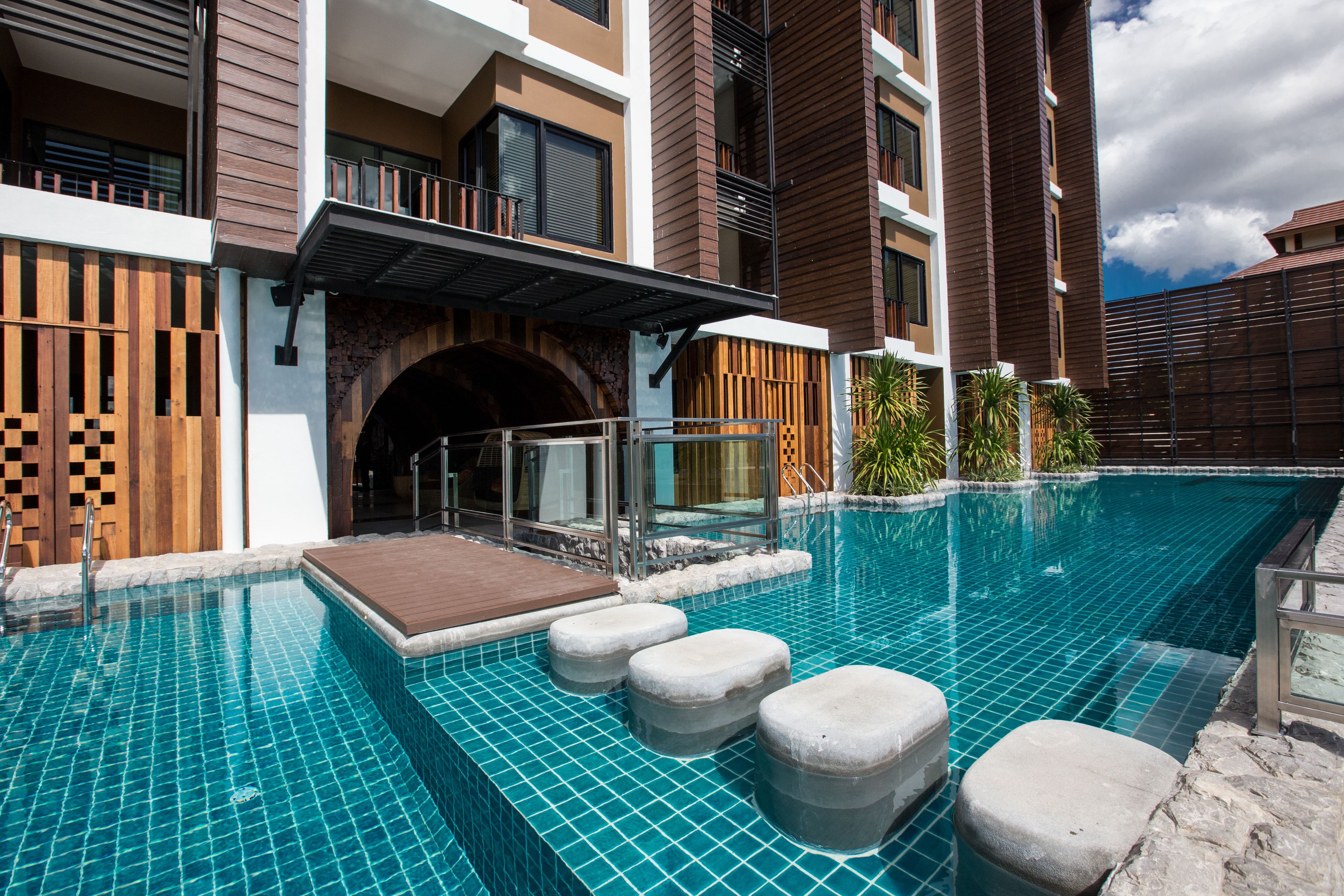 A modern hotel with a swimming pool, stone steps, and a wooden deck.