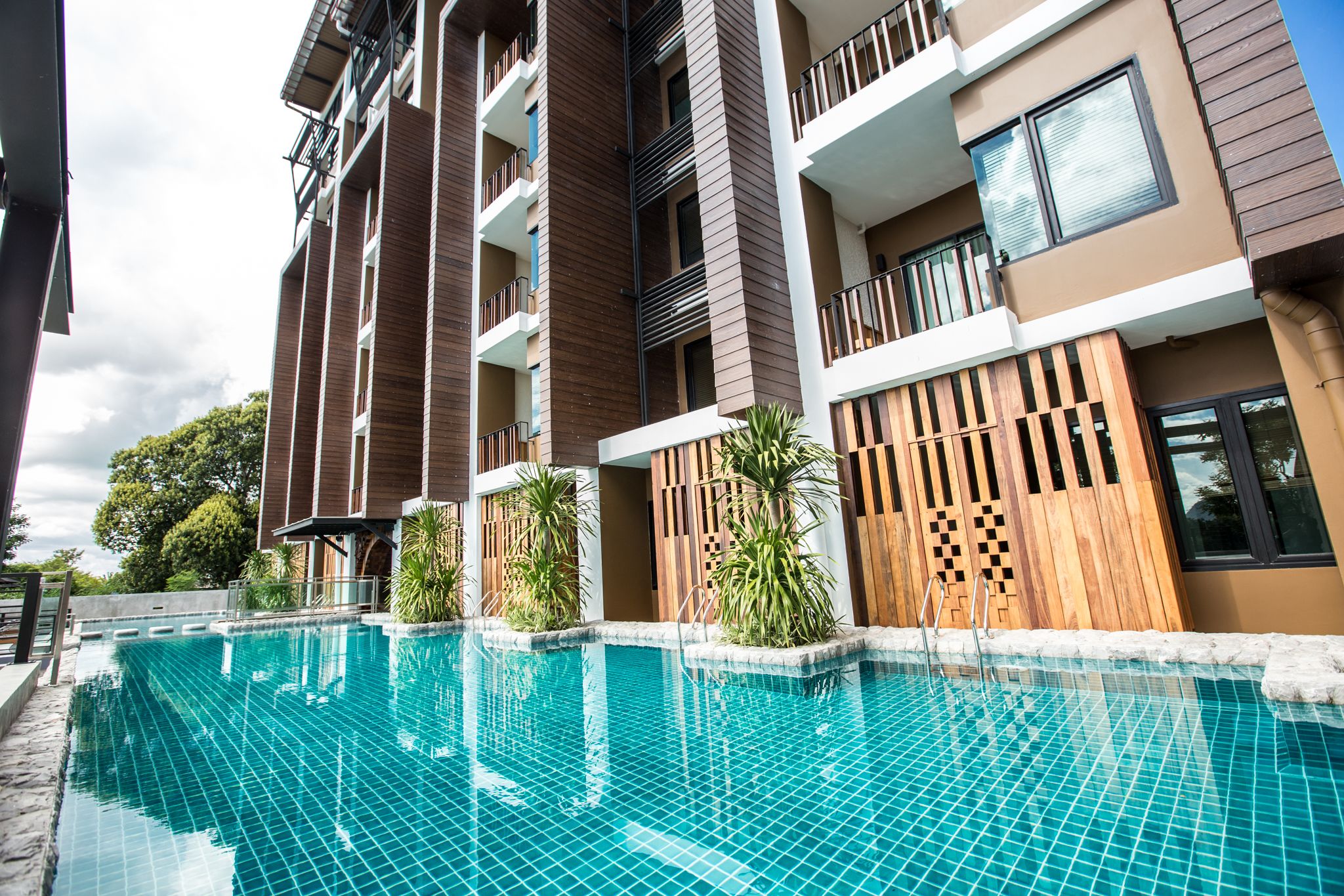 A modern building with a swimming pool, balconies, and wooden paneling.