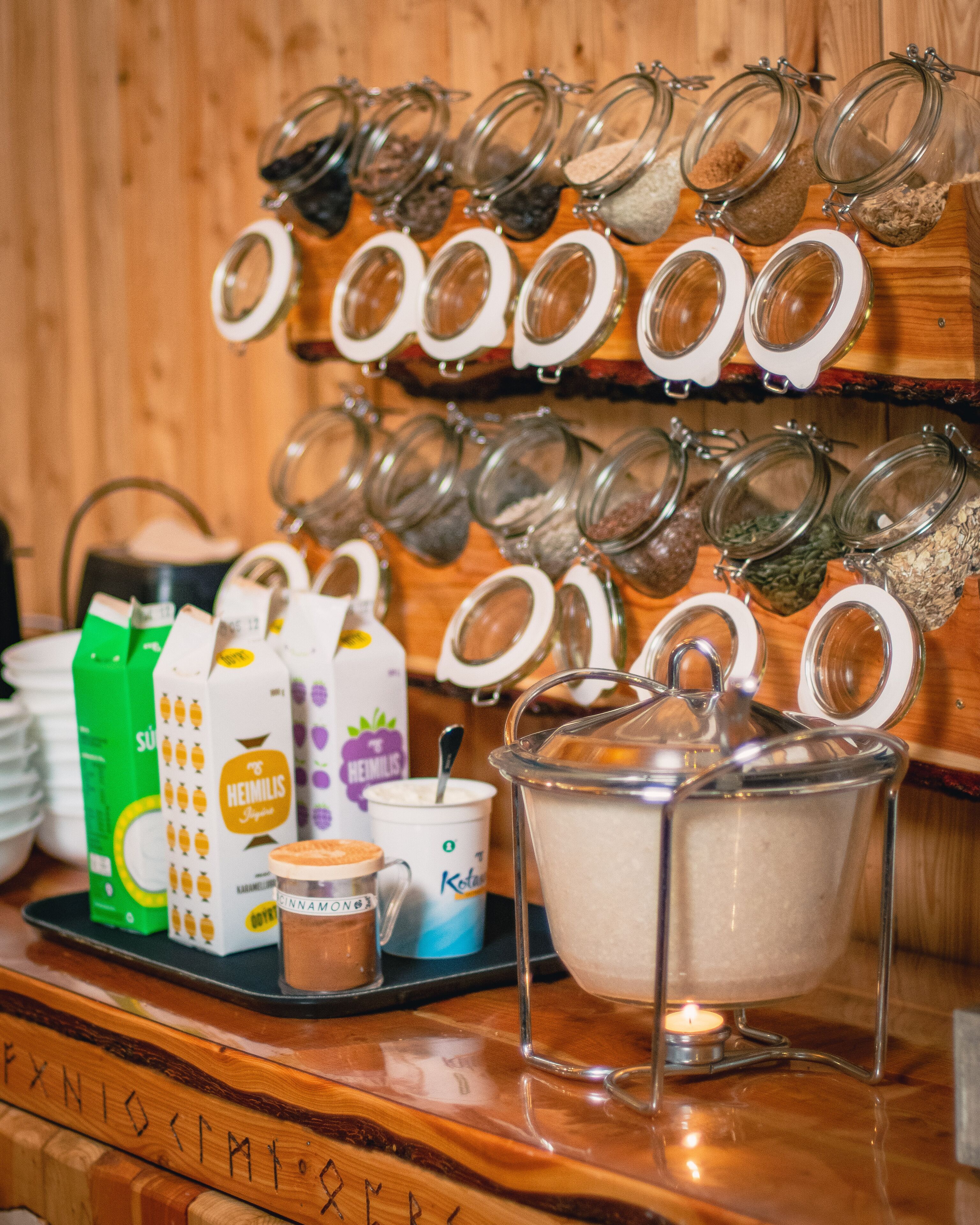Un buffet pour le petit-déjeuner proposant divers aliments et boissons, notamment des pots d’épices, des briques de lait et une cafetière.